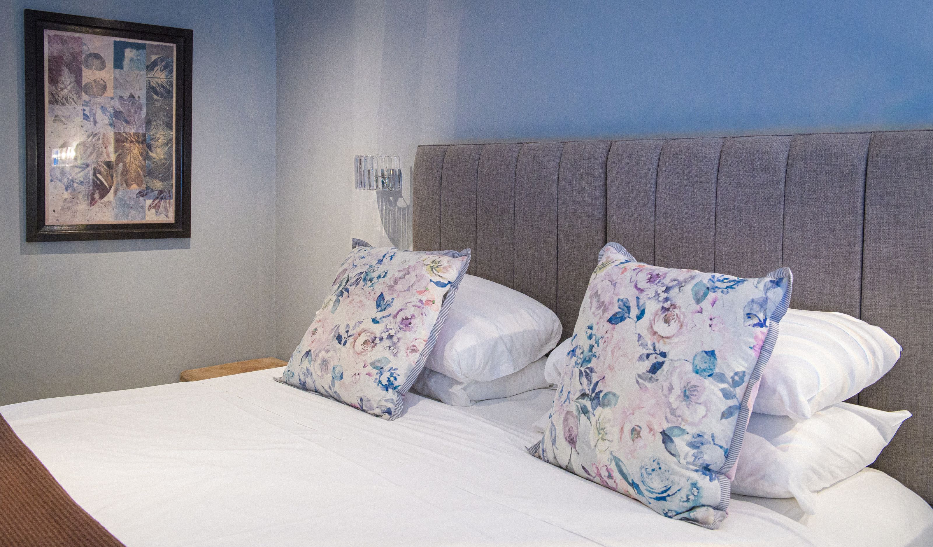 Floral cushions against a grey upholstered headboard in a bedroom at Sheene Mill