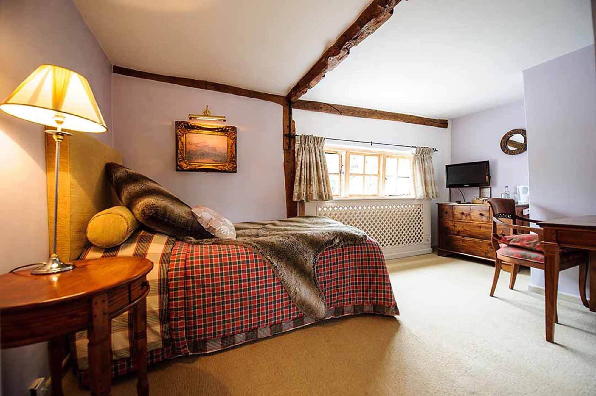 A boutique guest bedroom with exposed beams and seating at Sheene Mill, Cambridgeshire