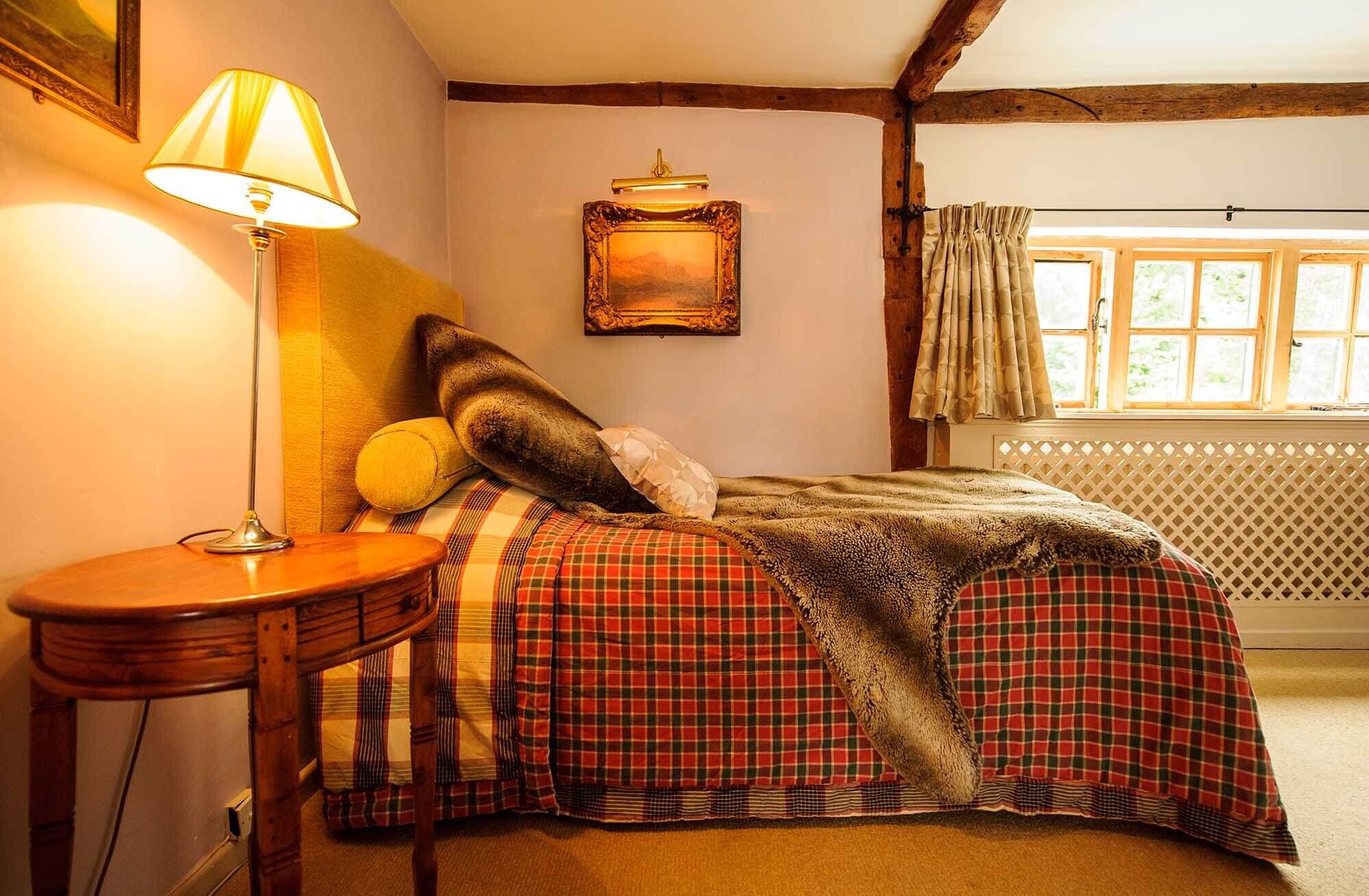 A boutique bedroom with exposed beams overlooking the River Mel at Sheene Mill, Cambridgeshire