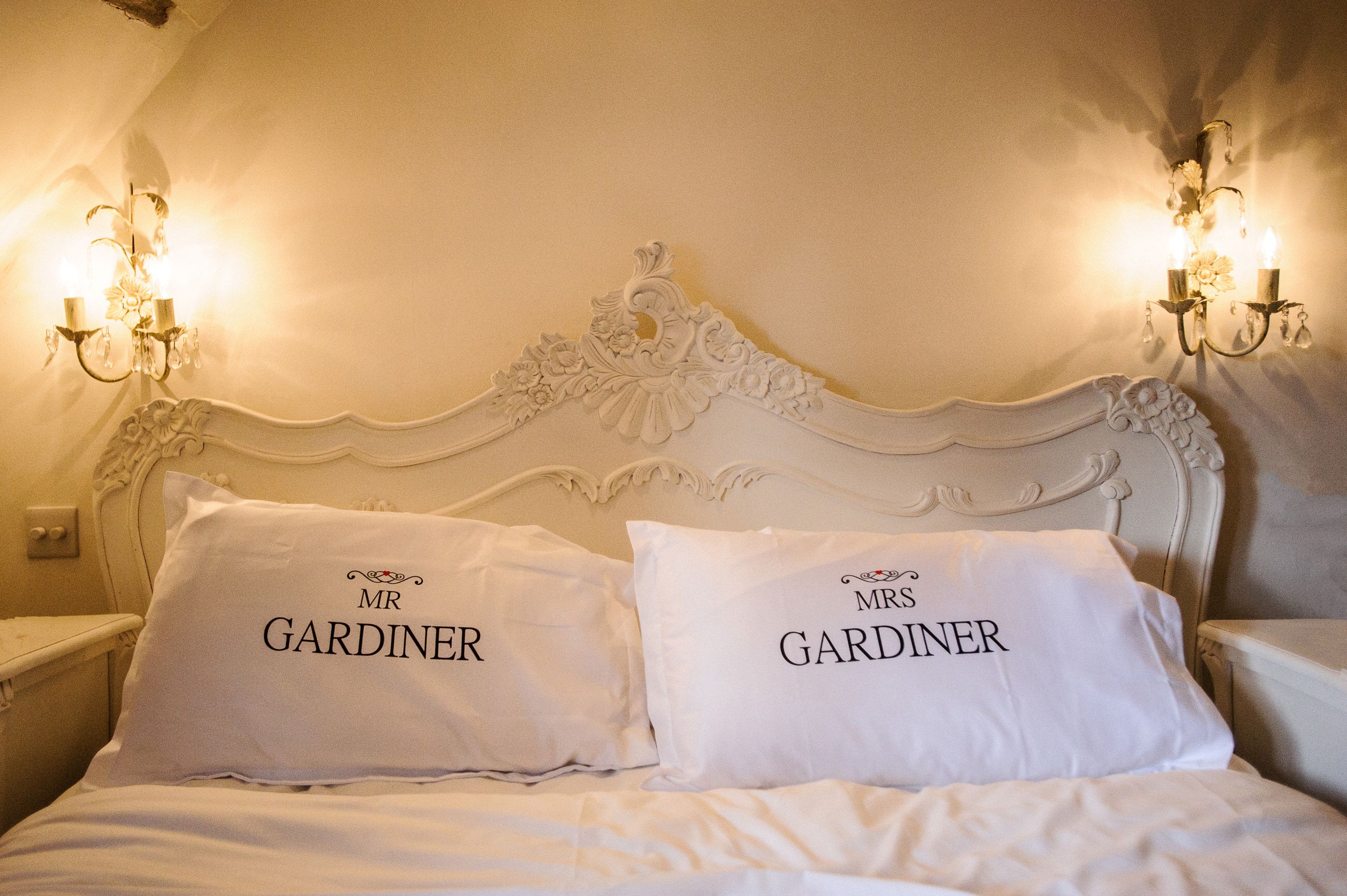 A carved white headboard and personalised pillowcases in the bridal suite at Sheene Mill