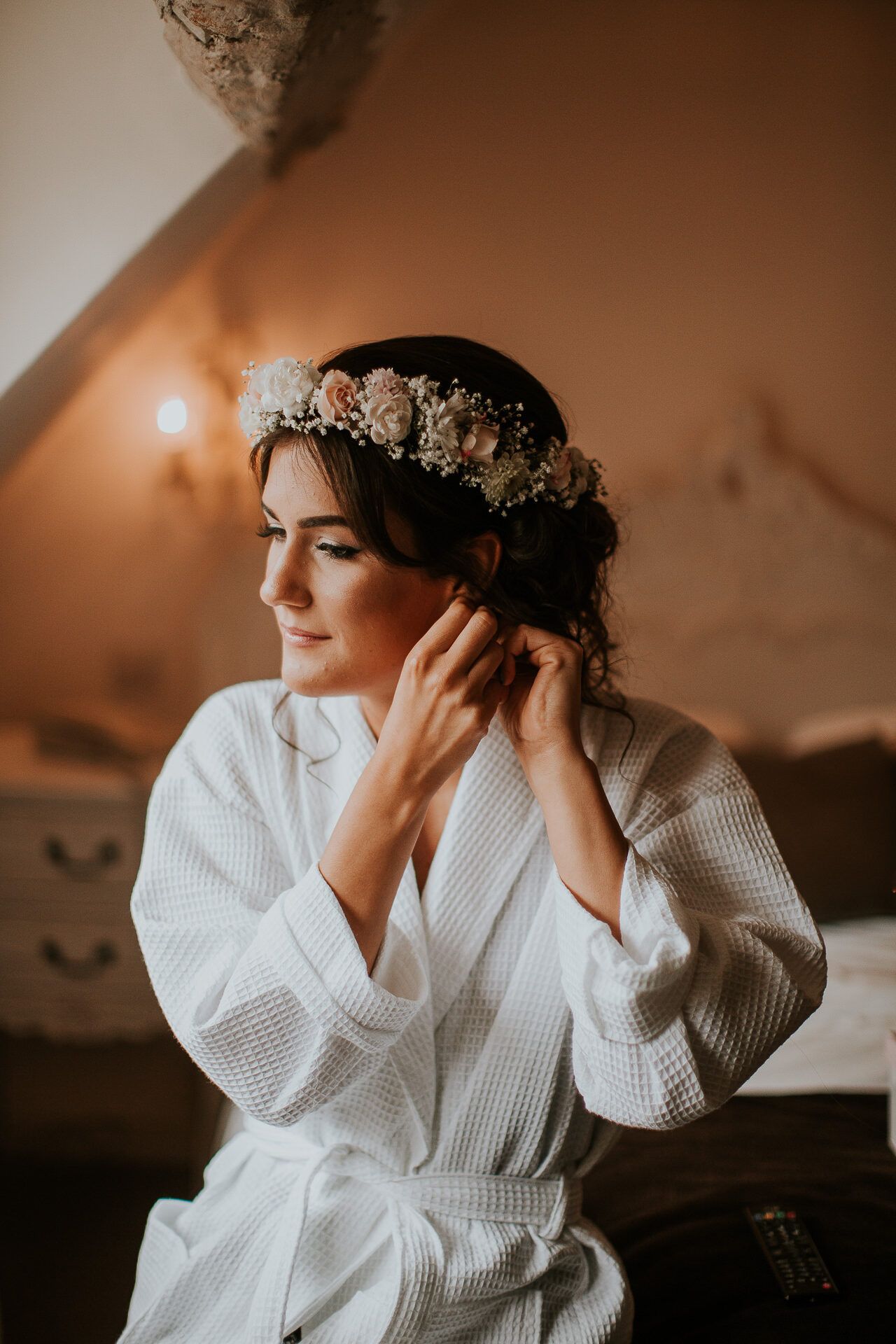 A bride wearing a flower crown getting ready in a robe at Sheene Mill