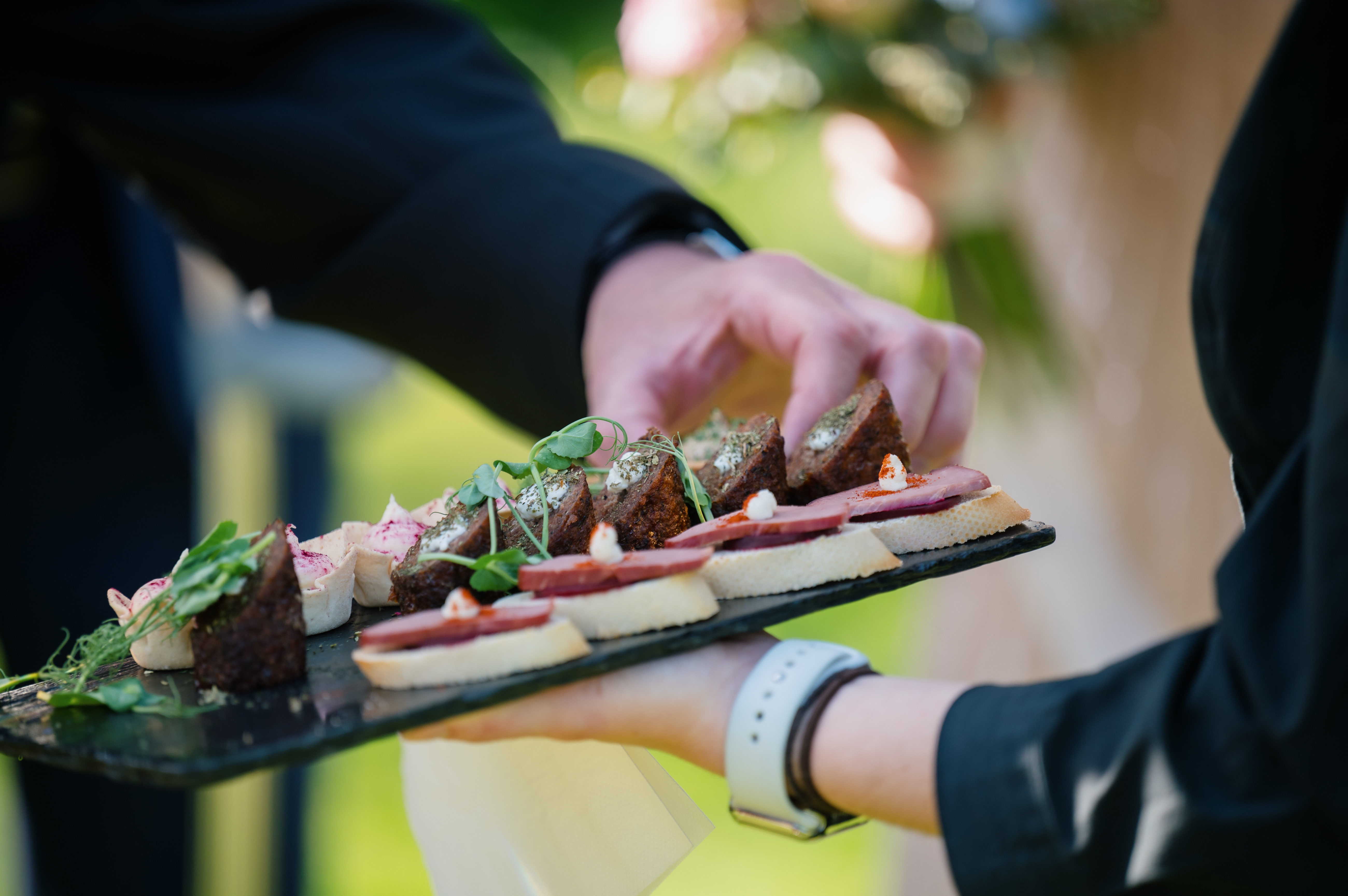 A tray of canapés on slate, garnished with pea shoots, served to guests at an event at Sheene Mill, Cambridgeshire