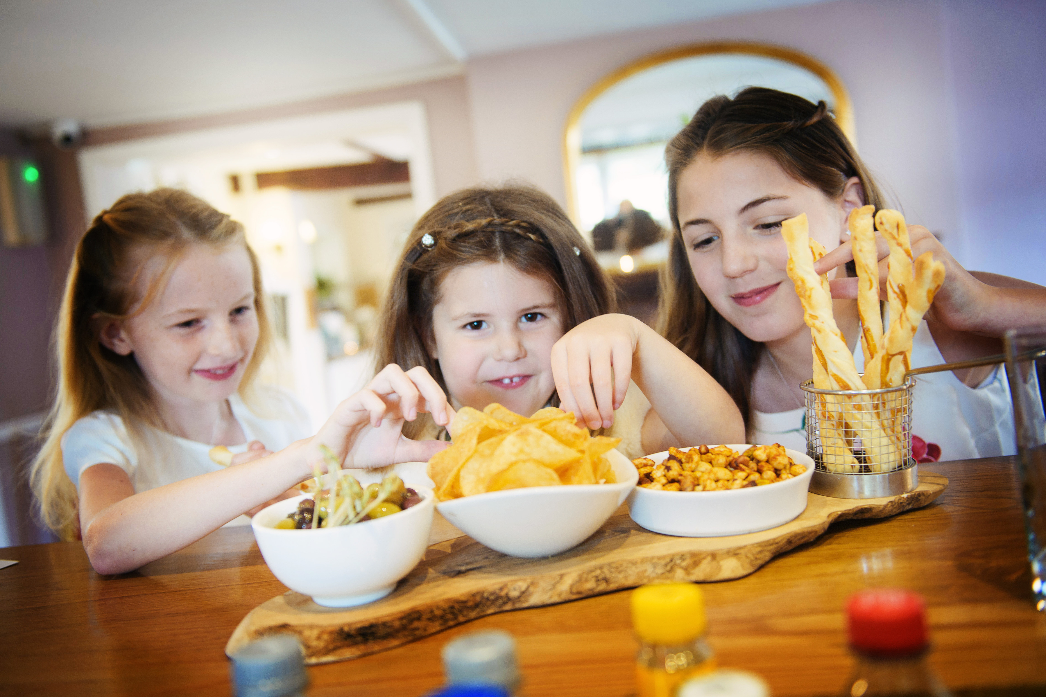 Three young guests sharing crisps, olives and breadsticks at a family celebration at Sheene Mill