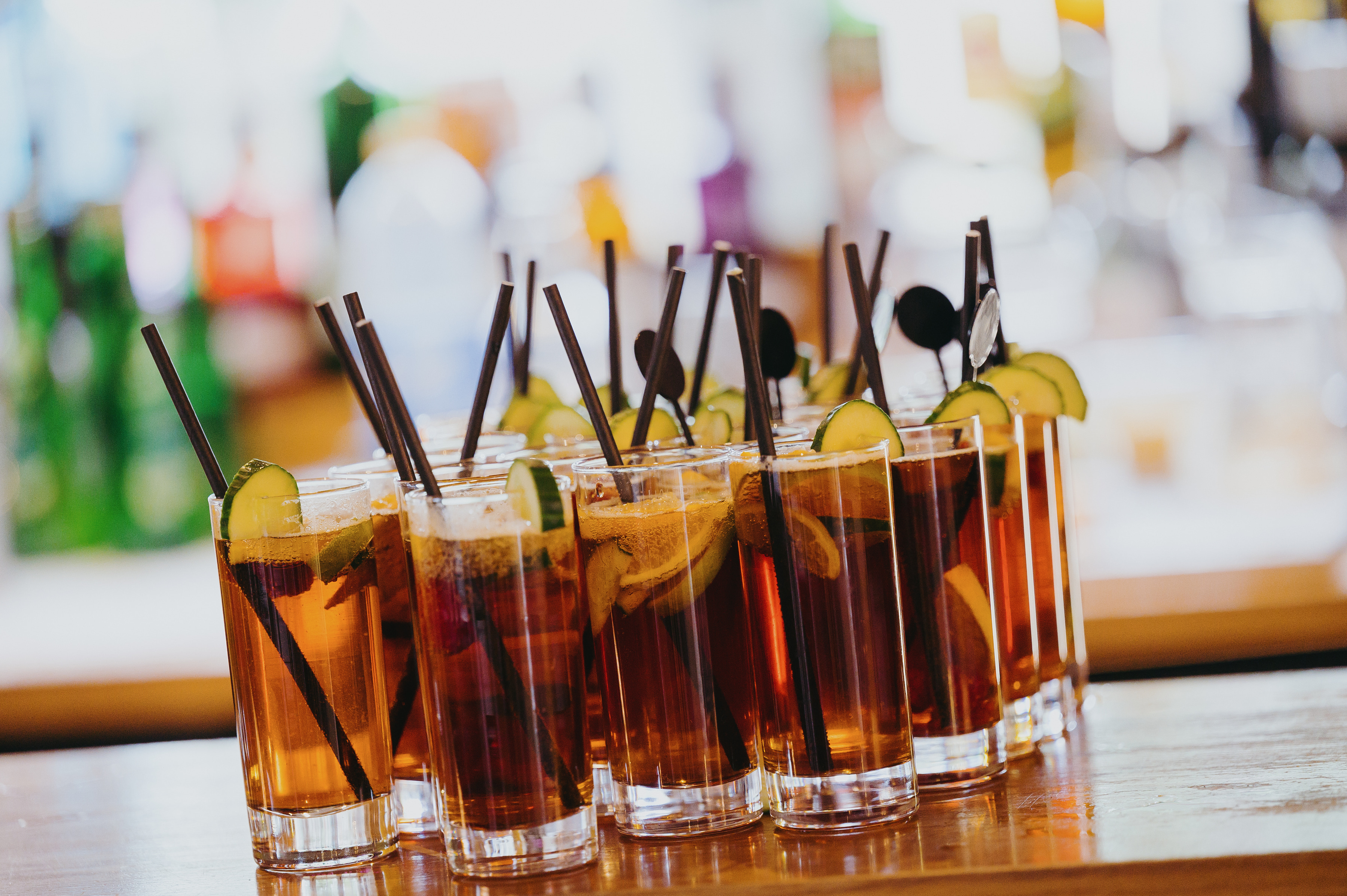 A row of cocktails with straws and citrus lined up on the bar at Sheene Mill