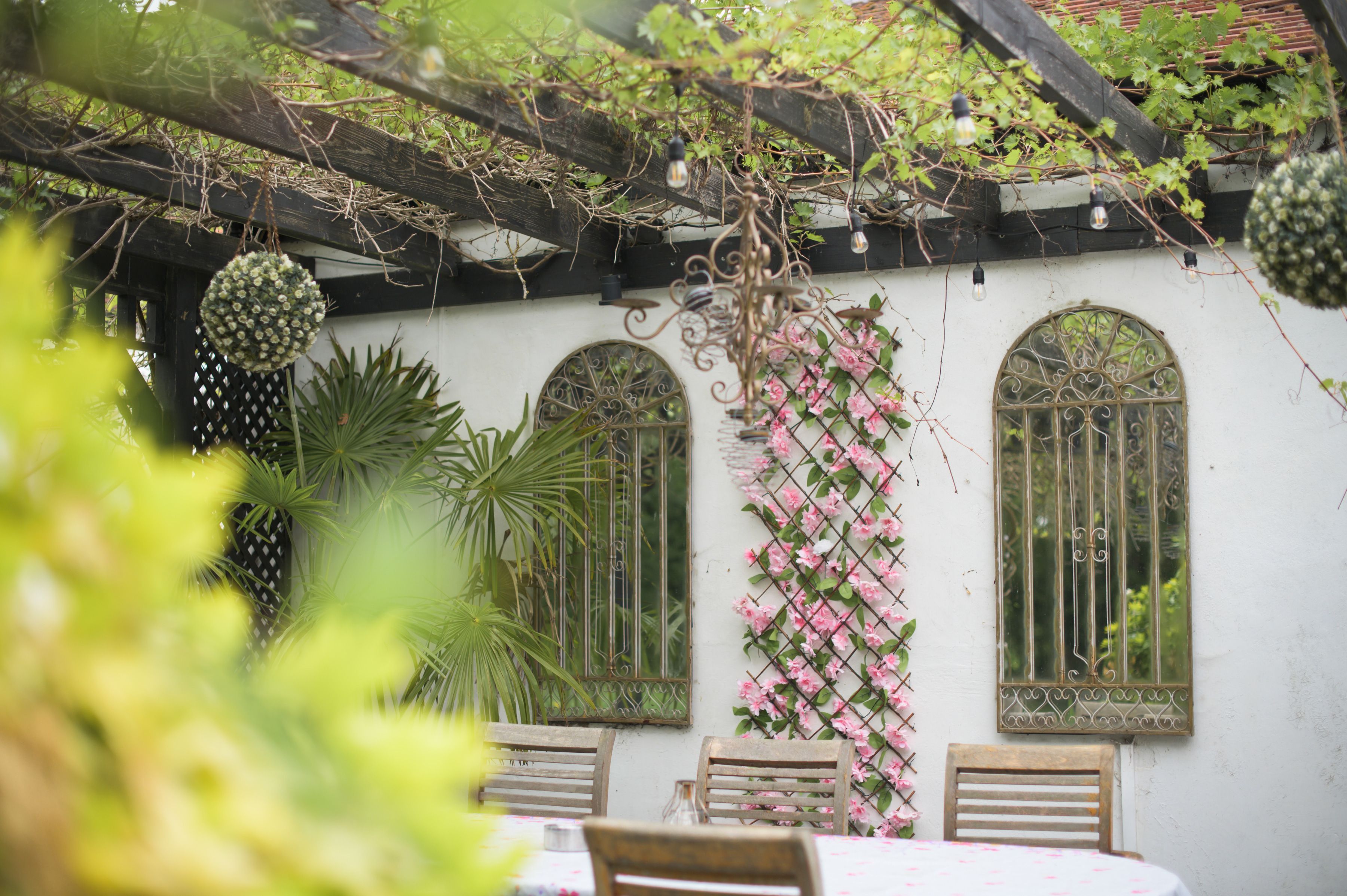 The courtyard terrace at Sheene Mill, set for dining under a pergola hung with festoon lights and pink blossom
