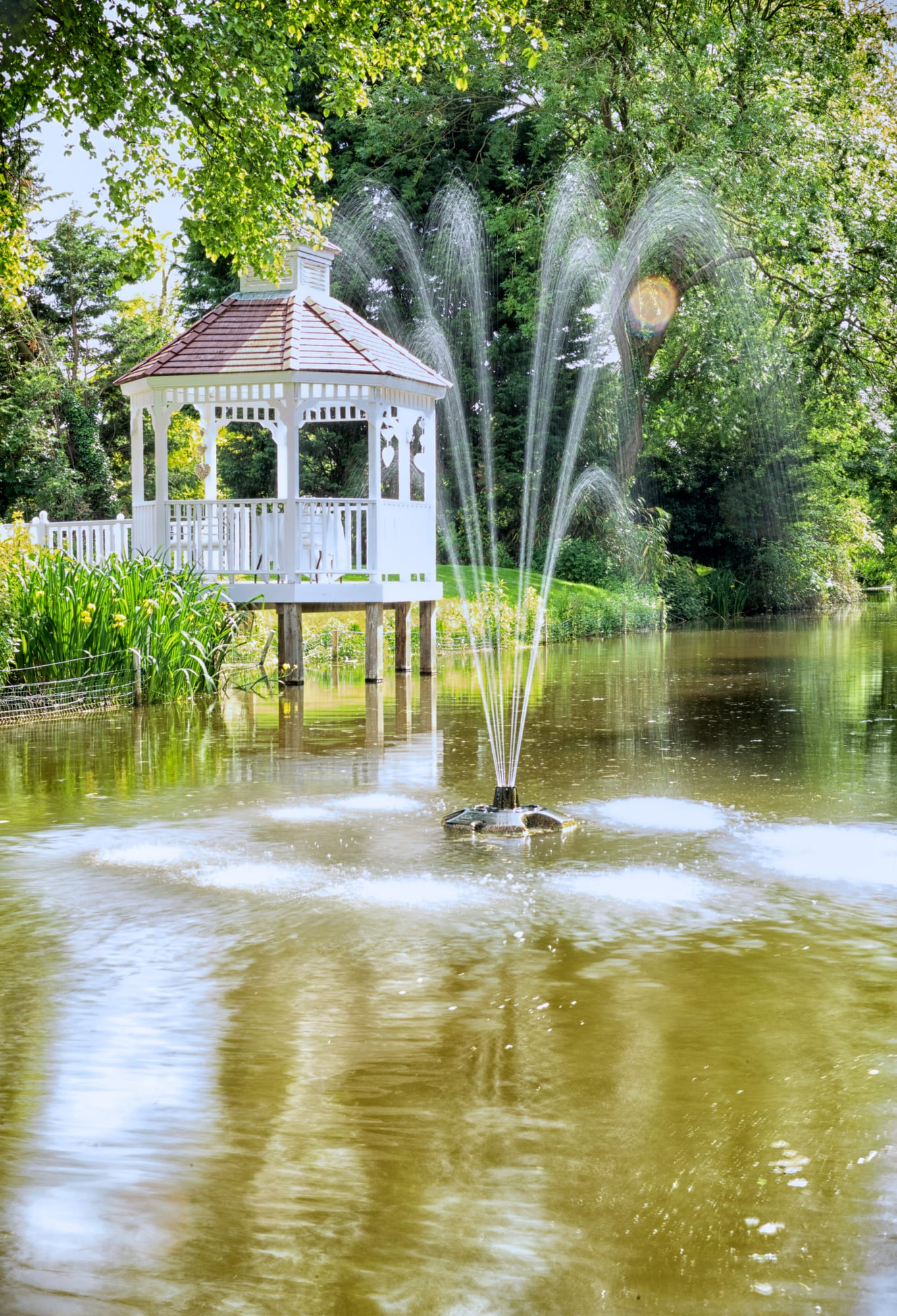 The white gazebo beside the fountain on the millpond at Sheene Mill in Cambridgeshire