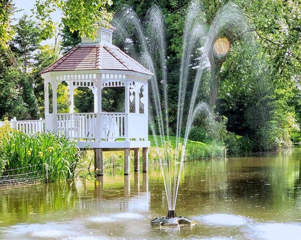 The white gazebo and fountain on the mill pond on a summer day at Sheene Mill