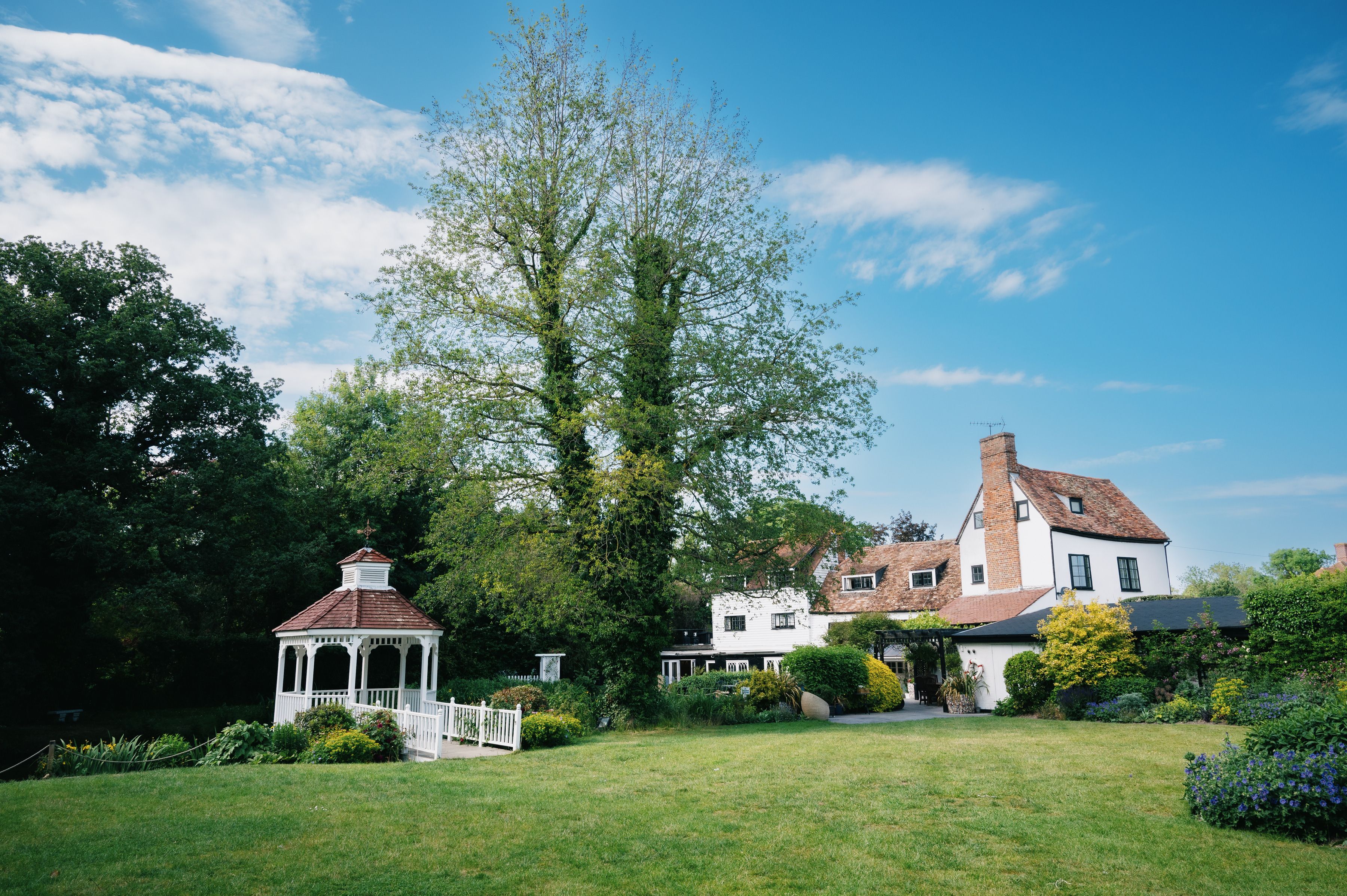 The white mill house, garden gazebo and lawn at Sheene Mill, a sixteenth century riverside venue in Melbourn, Cambridgeshire