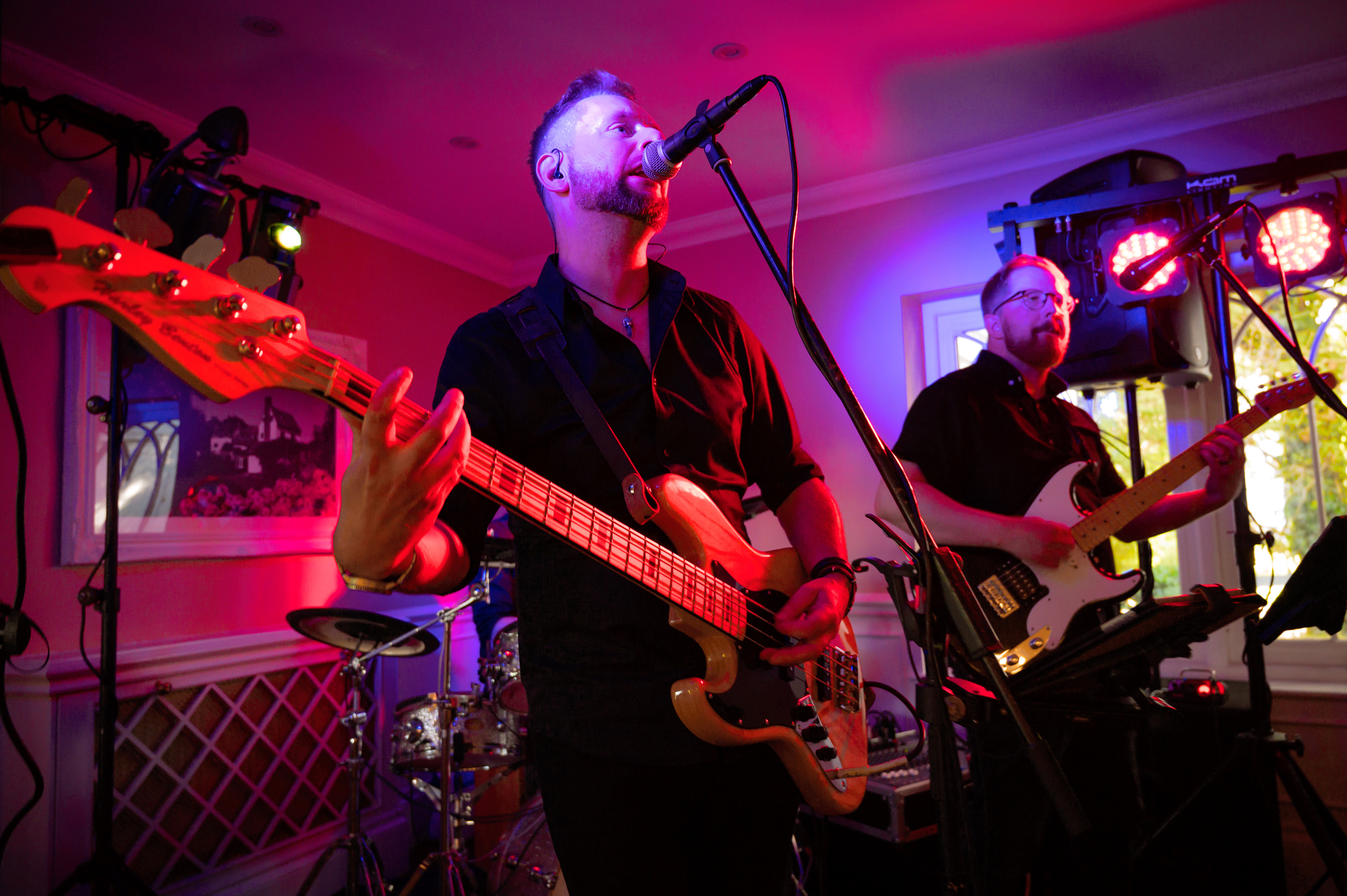 A live band playing under coloured lights at an evening party at Sheene Mill