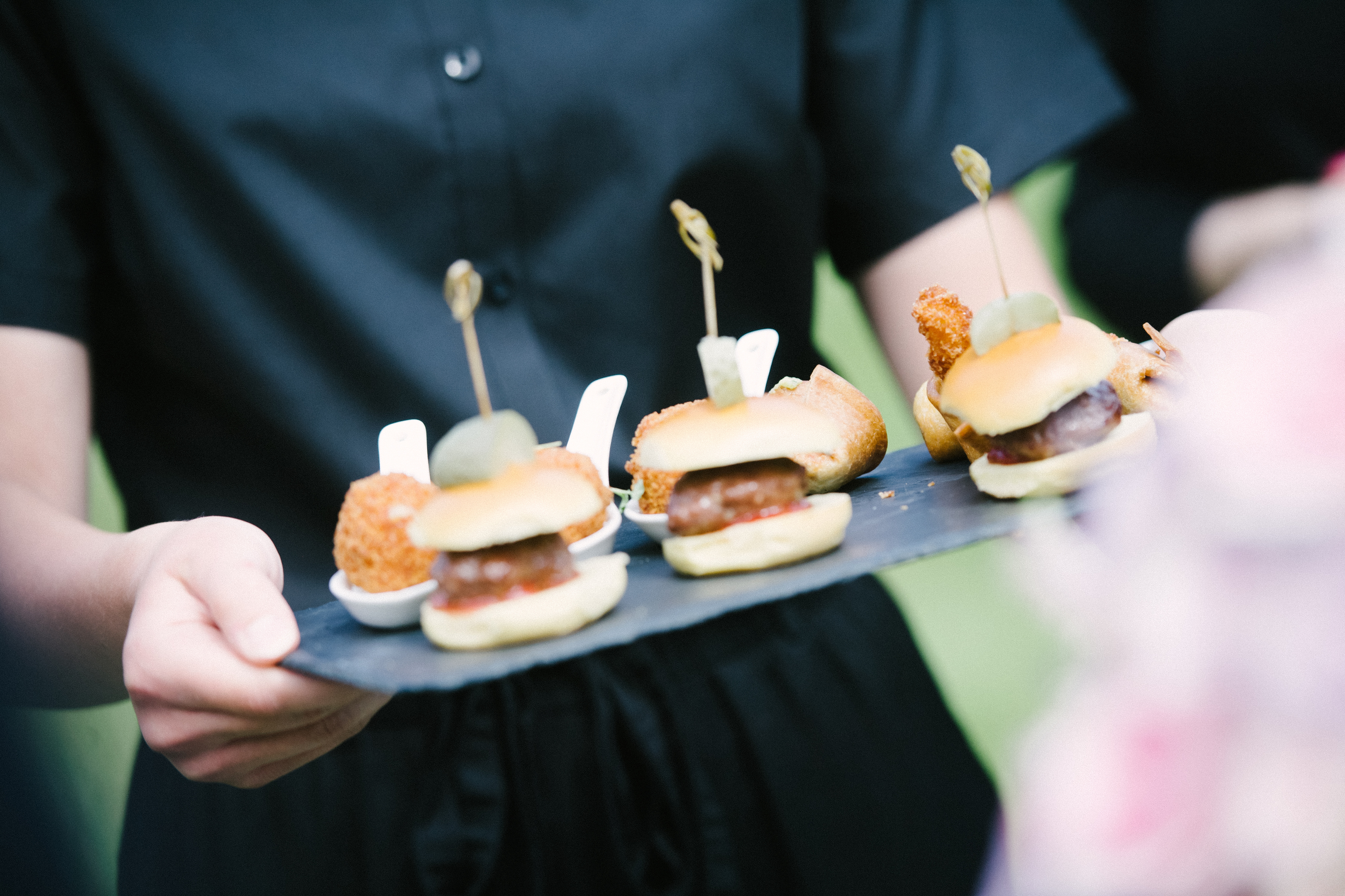 Mini burgers and canapés handed round on slate at a party at Sheene Mill