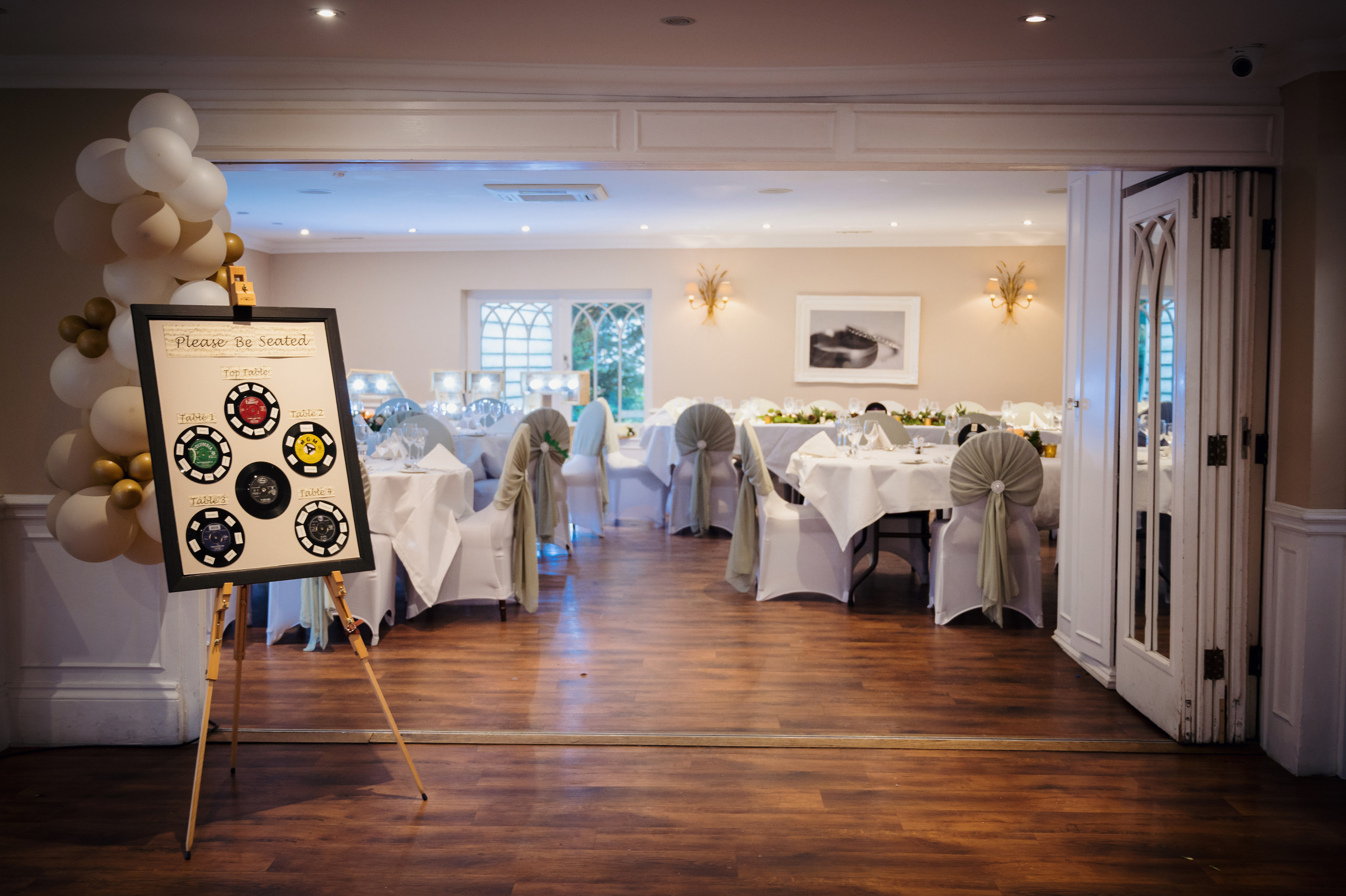 A balloon display and table plan at the entrance to a room set for a party at Sheene Mill