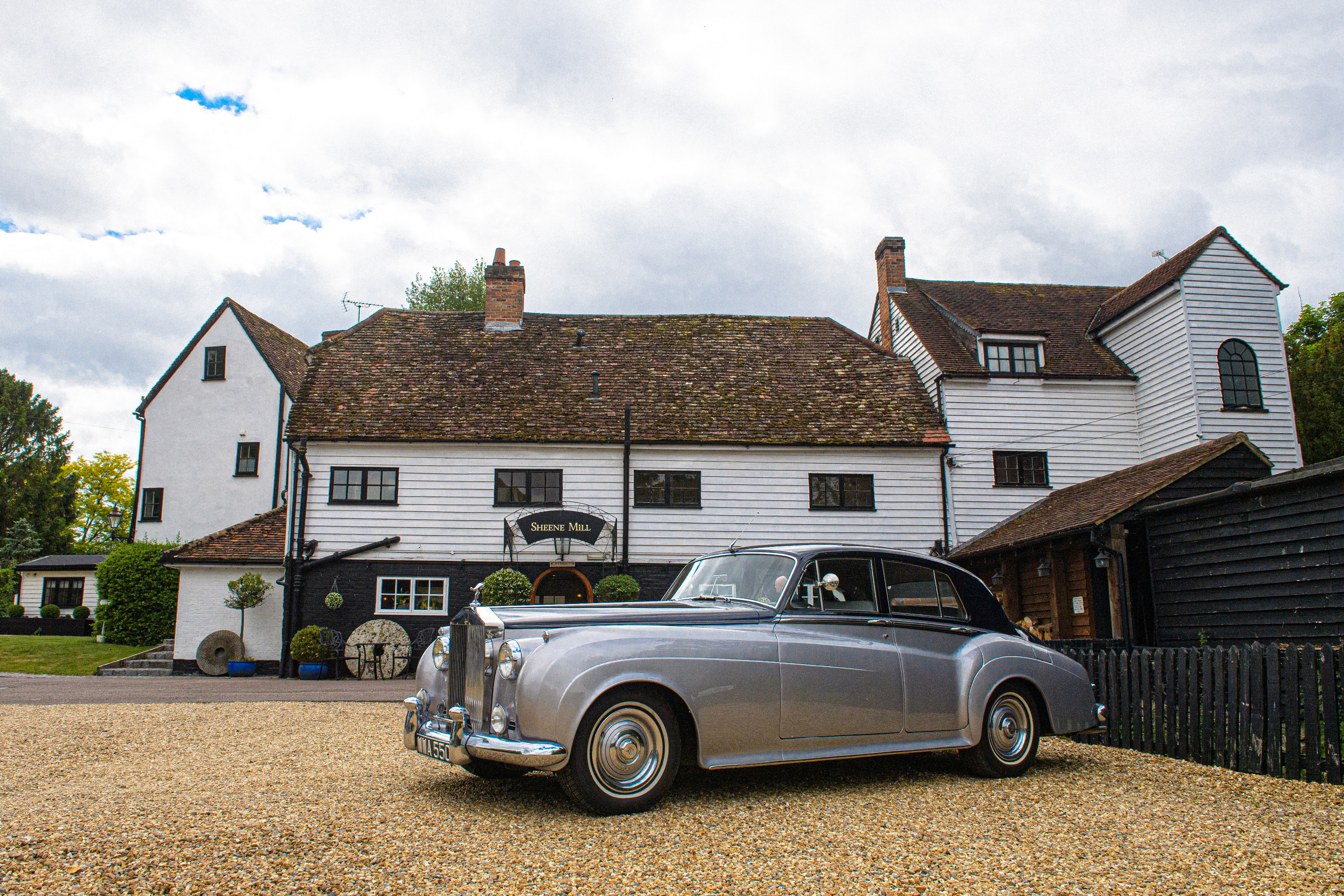A silver vintage Rolls-Royce on the gravel outside the white clapboard mill house at Sheene Mill in Cambridgeshire