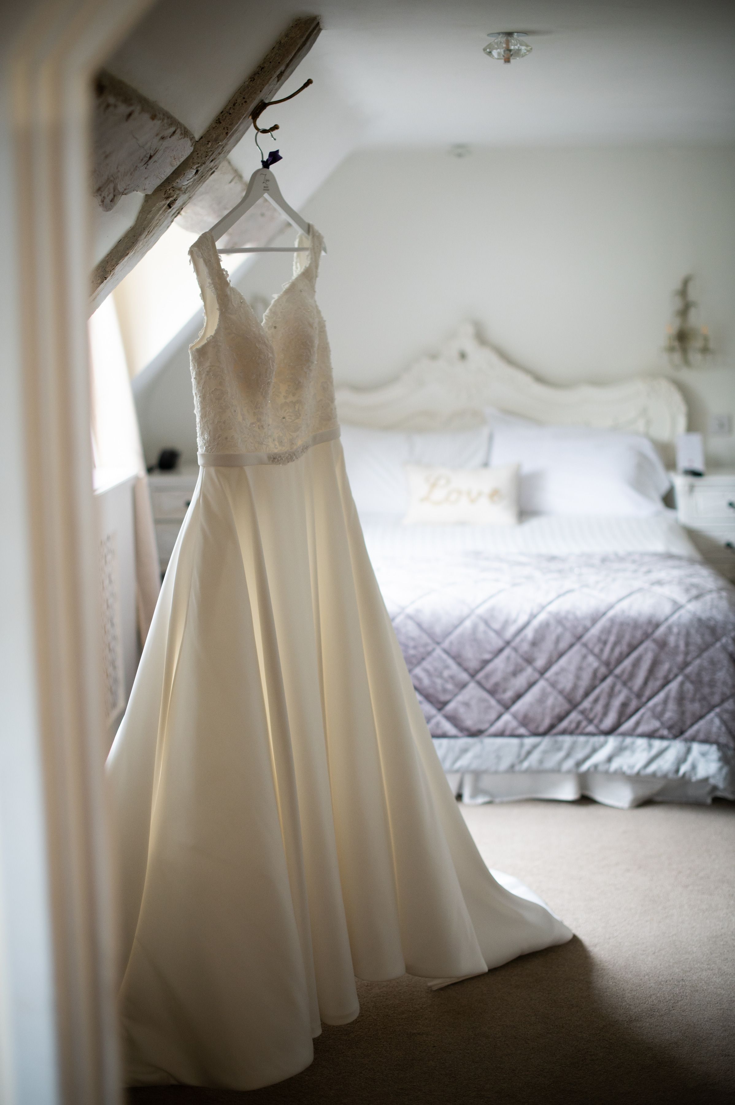 A wedding dress hanging in a beamed bedroom at Sheene Mill, Melbourn